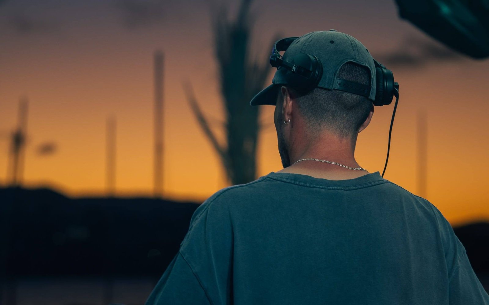 A DJ in headphones facing an orange sunset sky