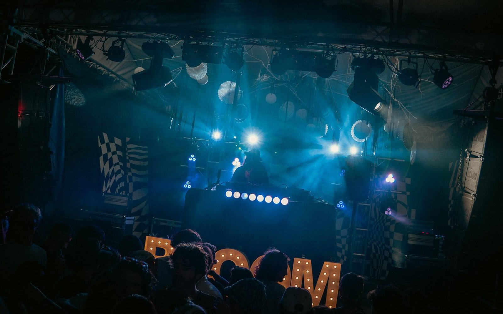 Open-air stage in blue light with BLOOM marquee letters in front of the crowd